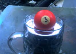 A pool ball floating in a cup of liquid Mercury.